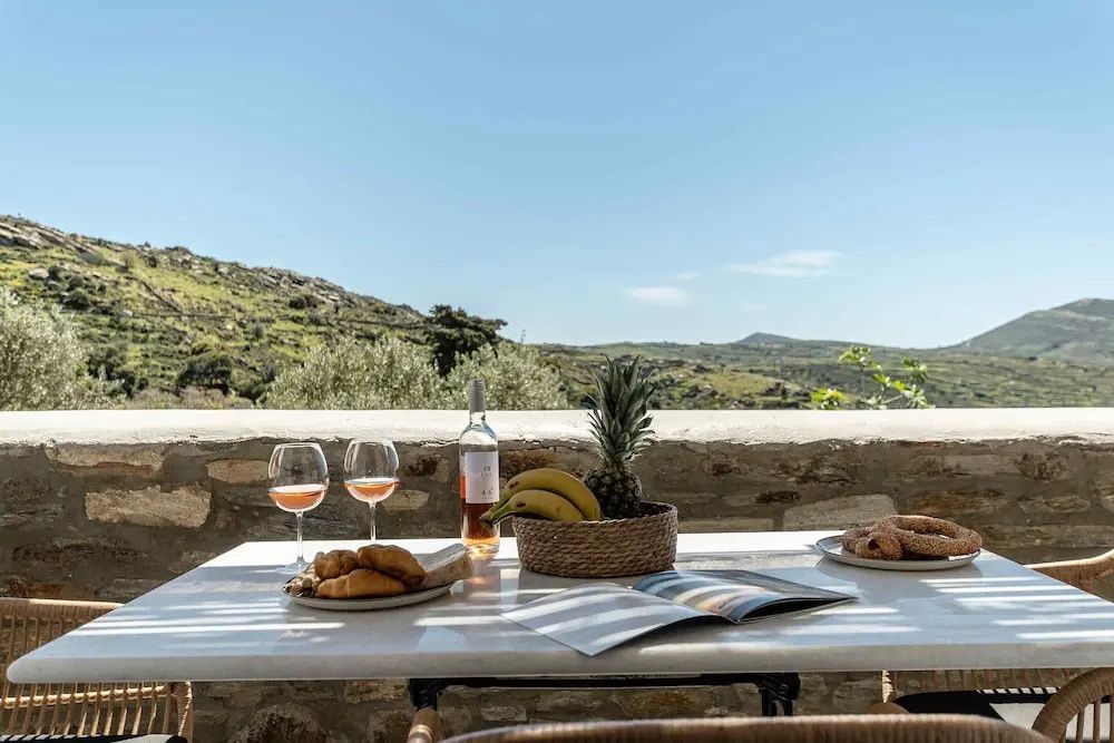 Gedeckter Tisch auf der Terrasse mit Blick auf grüne Hügel und blauen Himmel