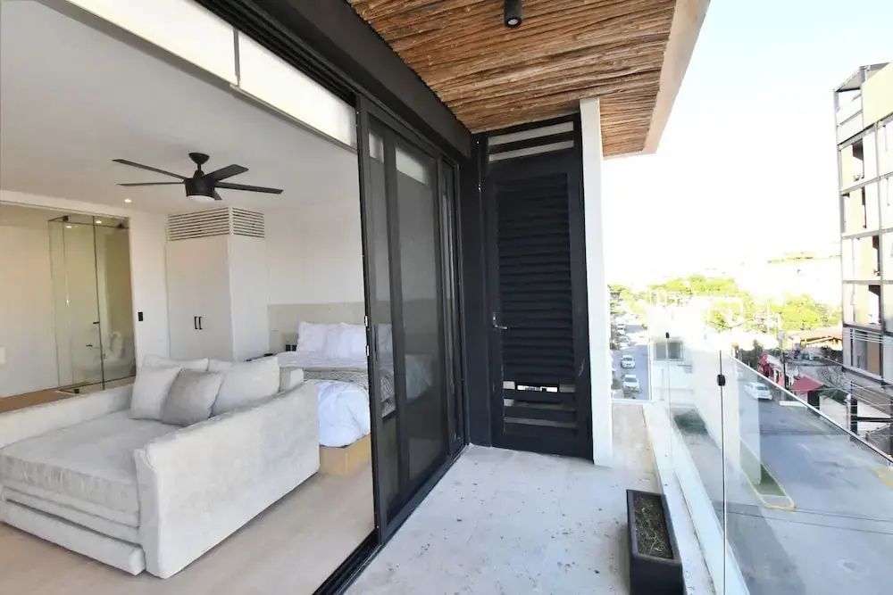 Überdachter Balkon mit Glasbrüstung und Schiebetür zum Schlafbereich der Suite.