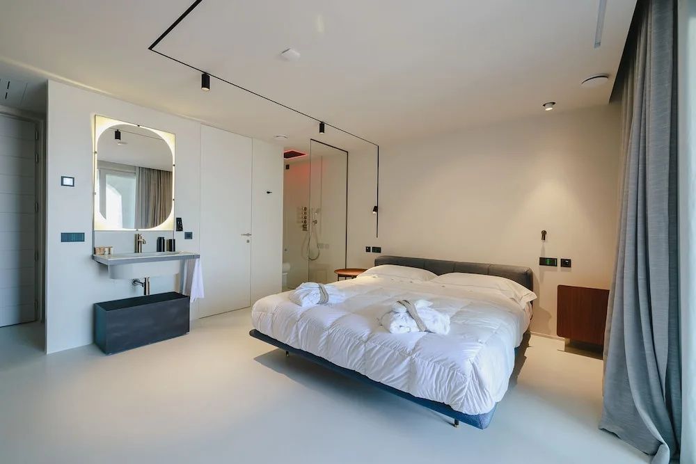 Modernes Hotelzimmer mit einem Doppelbett, zwei Bademänteln und offenem Waschbereich.