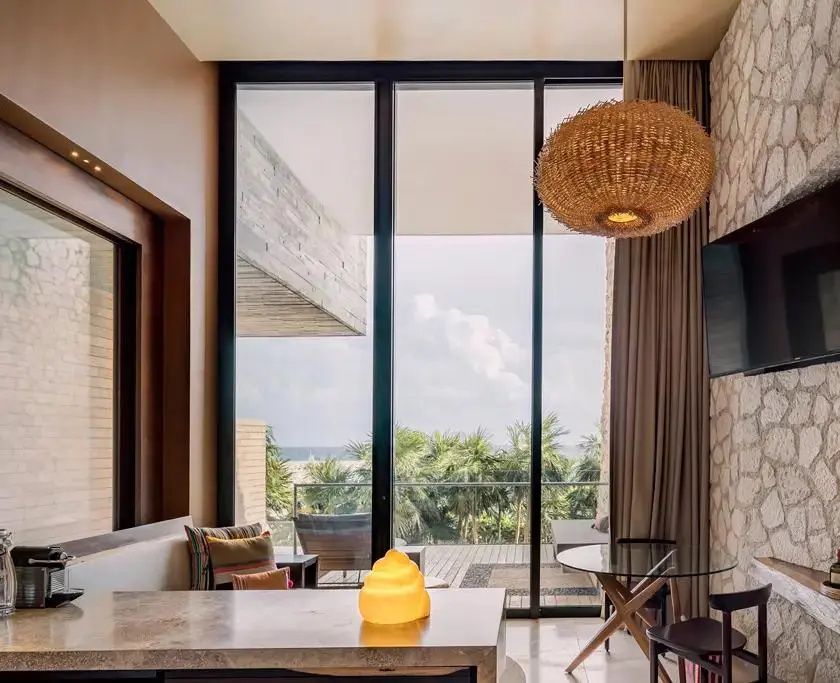 Große Fensterfront in einer Suite mit Blick auf den Balkon und Palmen