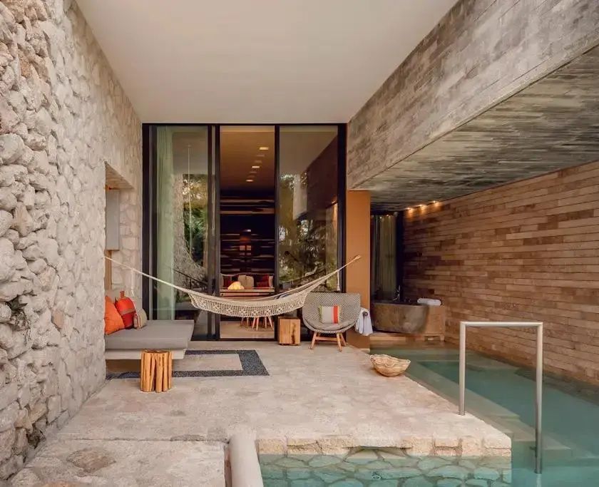 Überdachter Terrassenbereich mit Hängematte, Polstermöbeln und Zugang zu einem kleinen Pool.