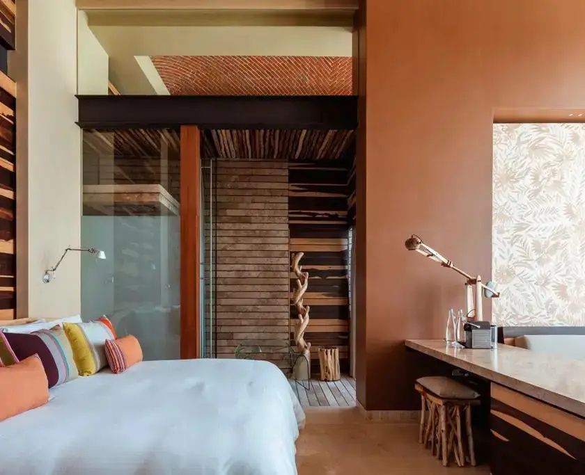 Zimmerecke mit Doppelbett, einem Schreibtisch aus Holz und Dekorelementen aus Naturmaterialien.