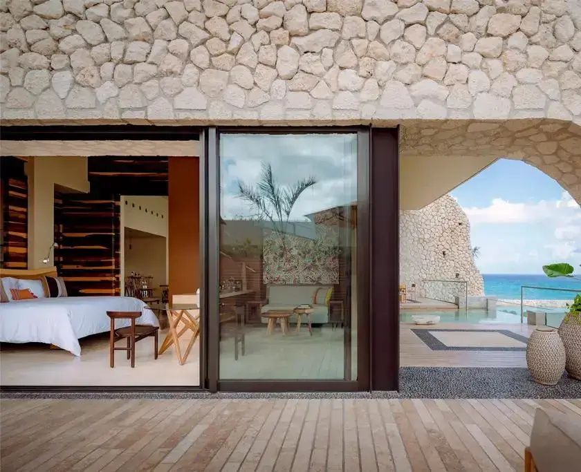 Terrasse einer Suite mit Schiebetüren zum Wohnbereich und Steinwand an der Fassade.