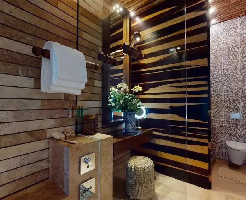 Badezimmerbereich mit hölzerner Wandverkleidung, Handtüchern und Waschtisch.