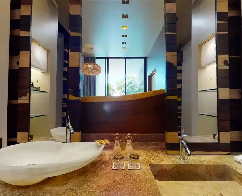 Badezimmer mit Doppelwaschbecken aus Naturstein und großen Spiegeln.