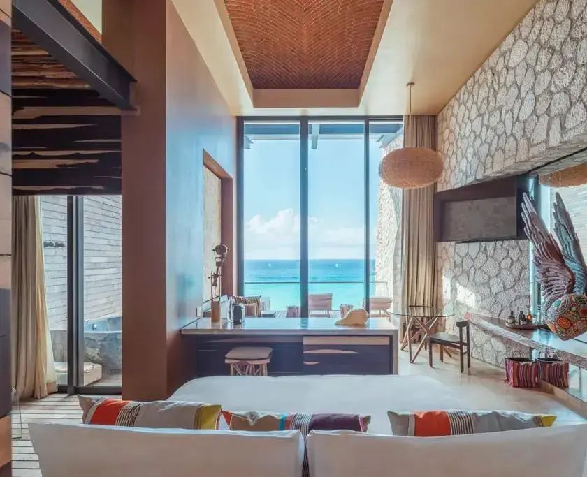 Schlafbereich einer Suite mit Blick durch eine große Fensterfront auf das Meer.