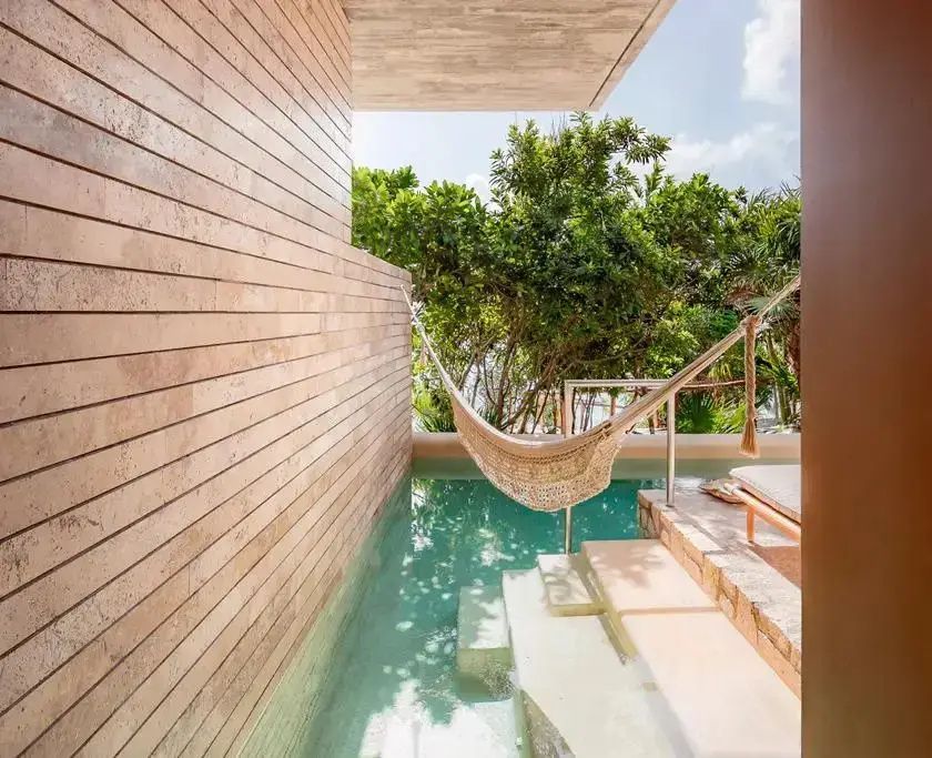 Privater Pool auf der Terrasse mit Einstiegstreppe, einer Hängematte und Holzwand im Hintergrund.