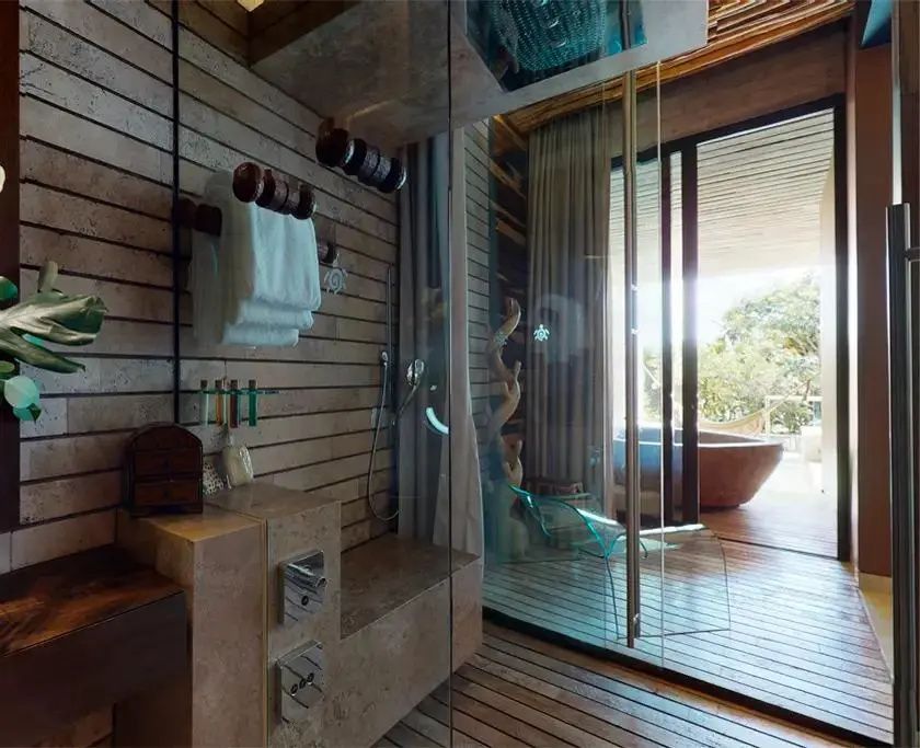 Verglaste Dusche im Badezimmer mit Handtuchhaltern aus Holz und Blick auf die Terrasse.