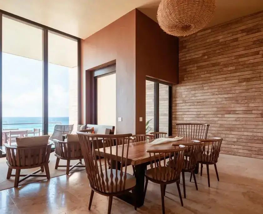 Essbereich in der Suite mit Holztisch, Holzstühlen und Blick auf den Ozean.