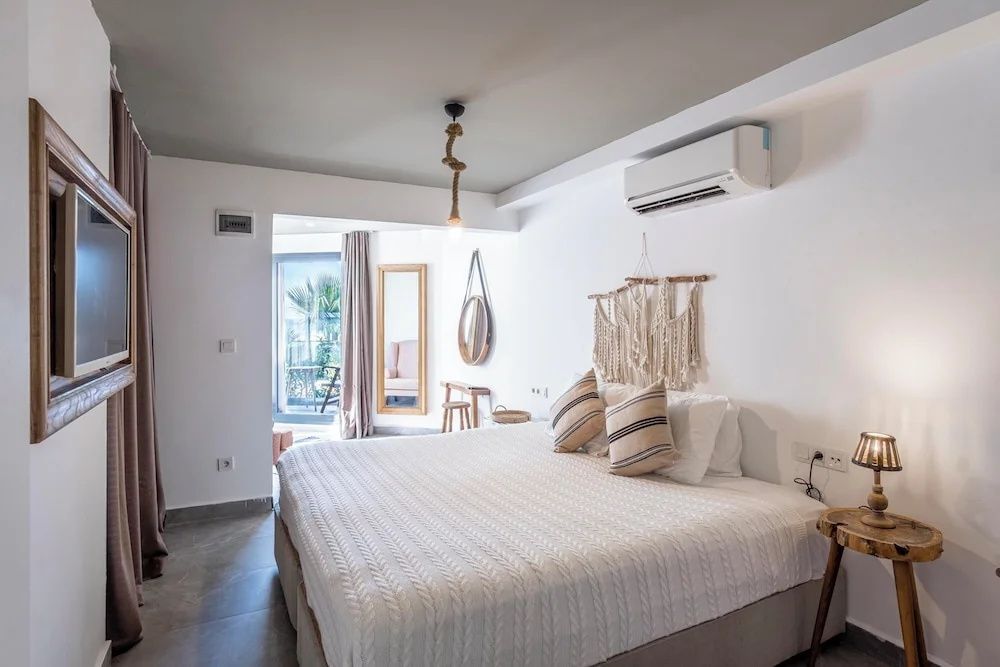 Schlafbereich mit großem Doppelbett, Wanddekoration aus Makramee und Balkonausgang.