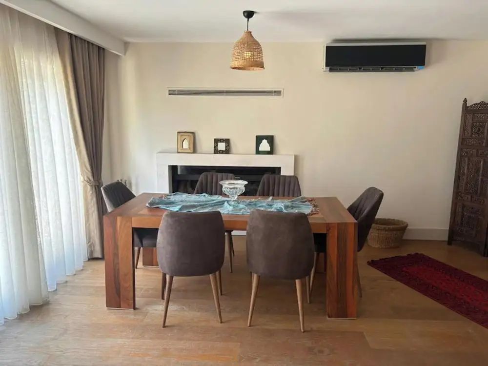 Essbereich mit Holz-Esstisch, gepolsterten Stühlen und Hängeleuchte im Zimmer.