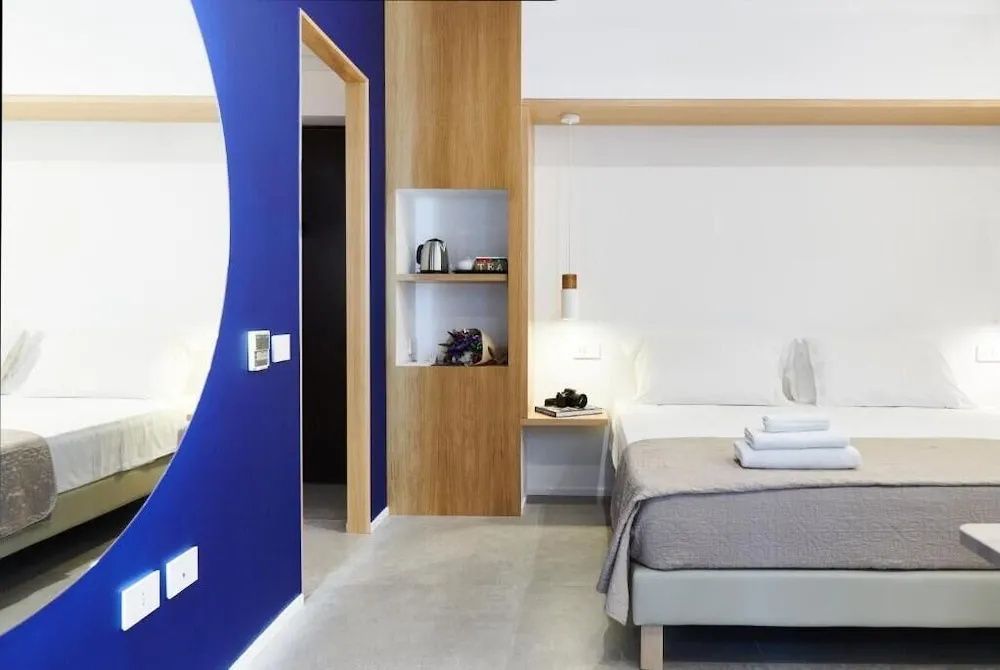 Modernes Zimmer mit Bett, blauer Wandgestaltung und integriertem Regal aus Holz.