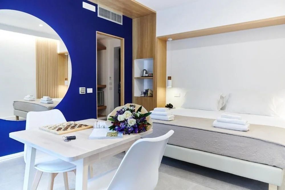 Sitzbereich im Zimmer mit Blumenstrauß auf dem Tisch, Bett und blauer Dekowand.