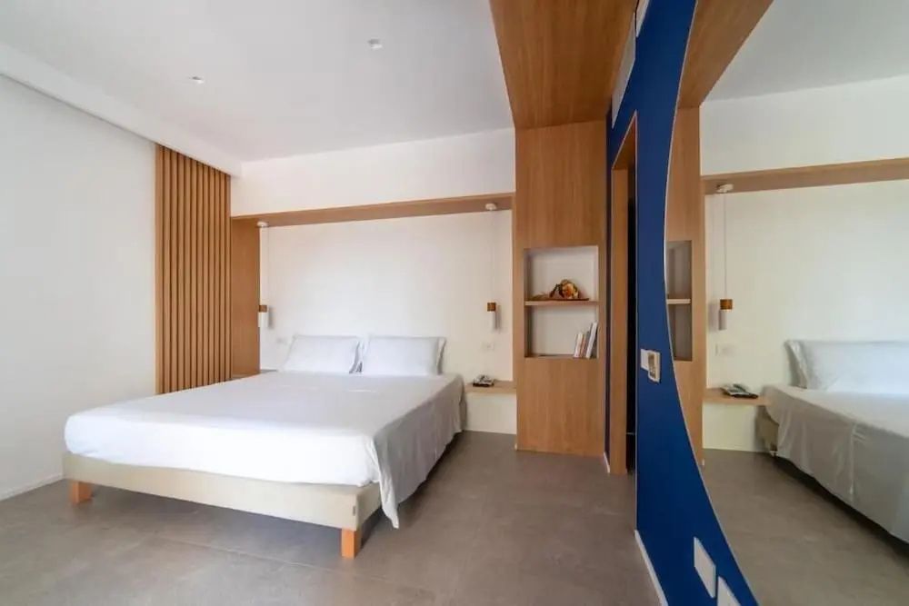 Schlafzimmer im Hotel mit großem Doppelbett, Holzverkleidung und blauer Wand.