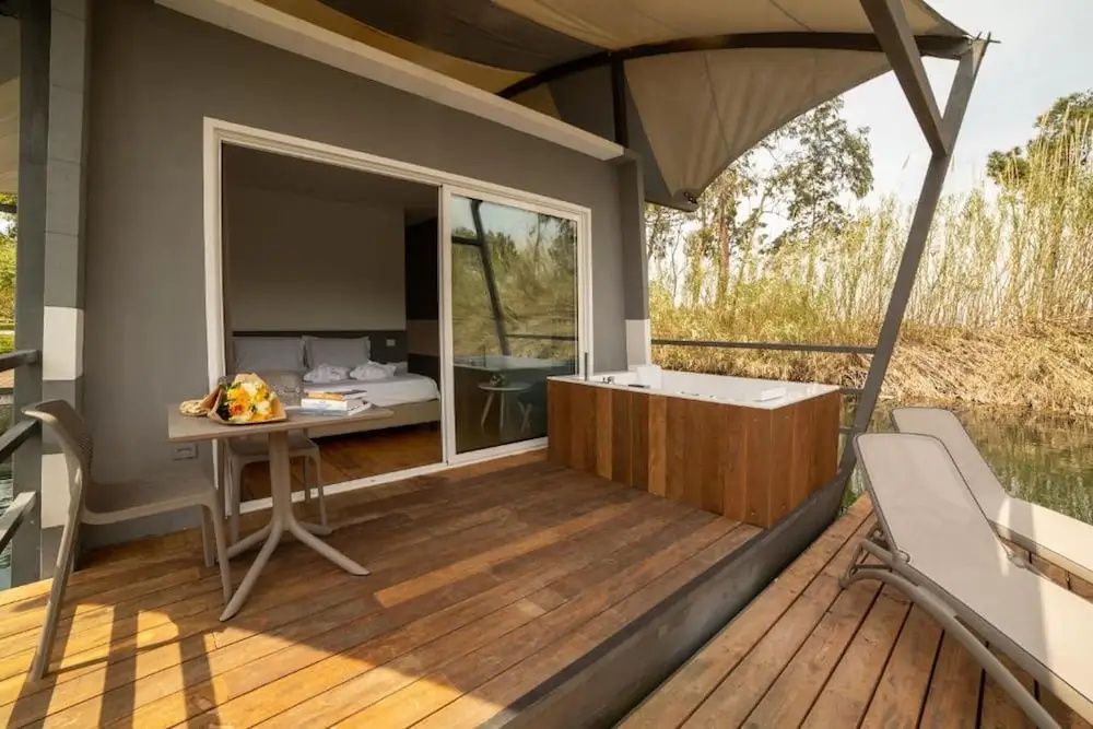 Holzterrasse mit eingebautem Whirlpool, Esstisch und Schiebetür zum Schlafzimmer.