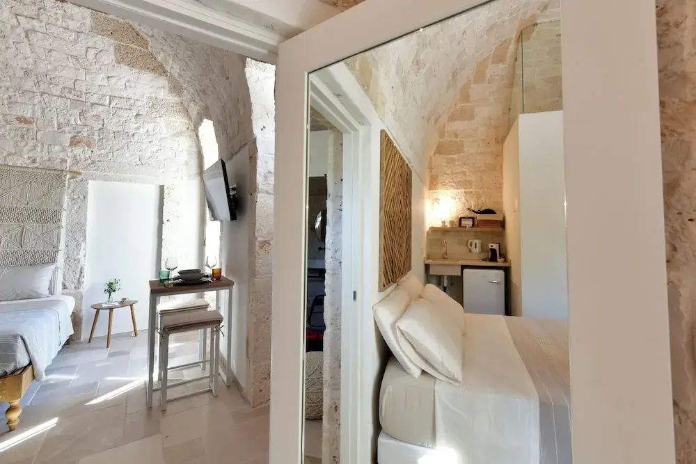 Blick in eine Suite mit hellen Natursteingewölben, Bett und kleinem Essbereich.