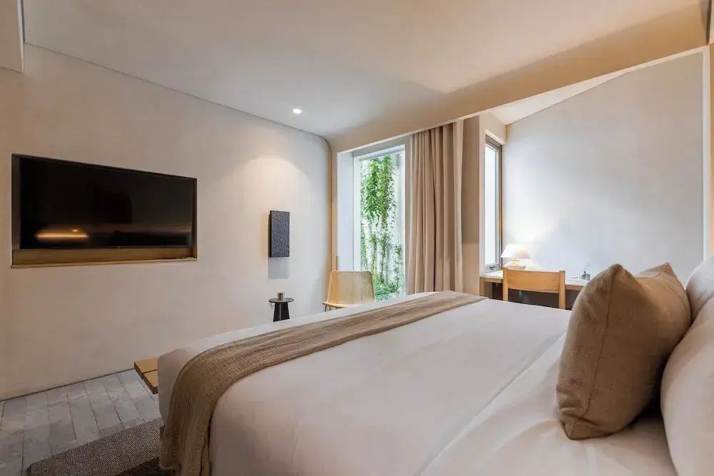 Modern eingerichtetes Hotelzimmer mit Doppelbett, Wand TV und Blick ins Grüne.