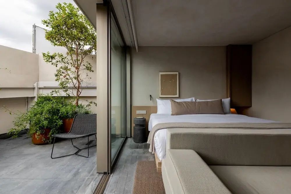 Modernes Schlafzimmer mit Doppelbett und großer Schiebetür zum bepflanzten Balkon.