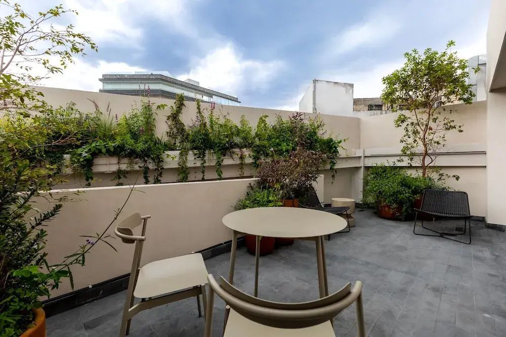 Möblierte Terrasse mit rundem Tisch, Stühlen und vielen Pflanzen.