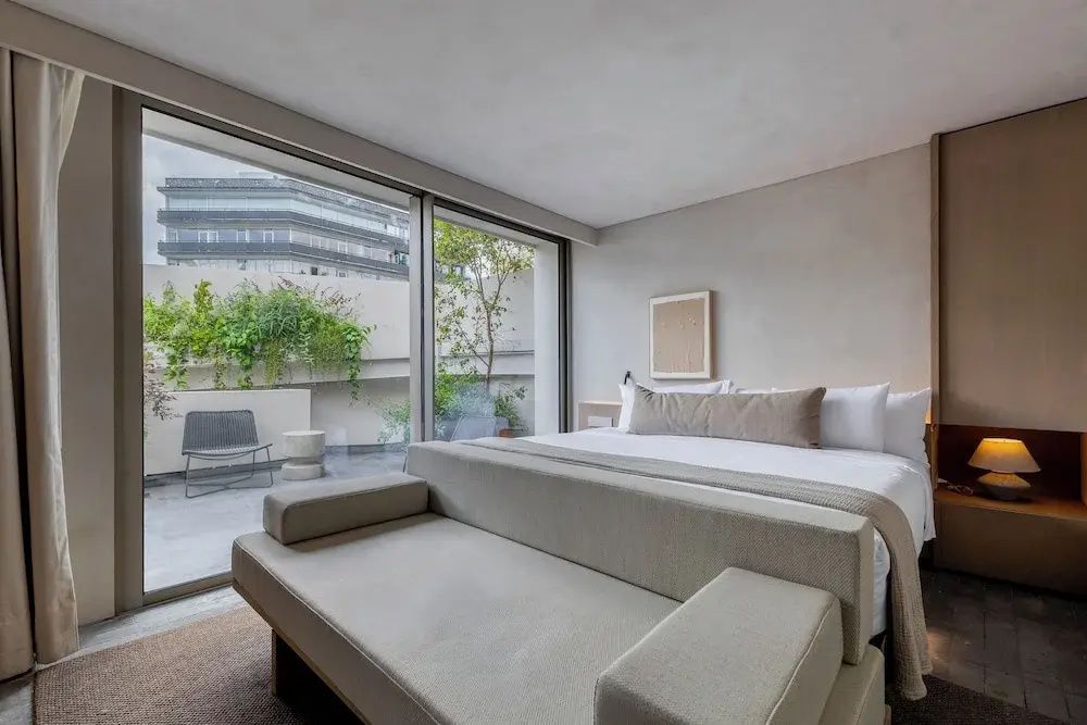 Schlafbereich mit großem Doppelbett und Blick auf die Terrasse.