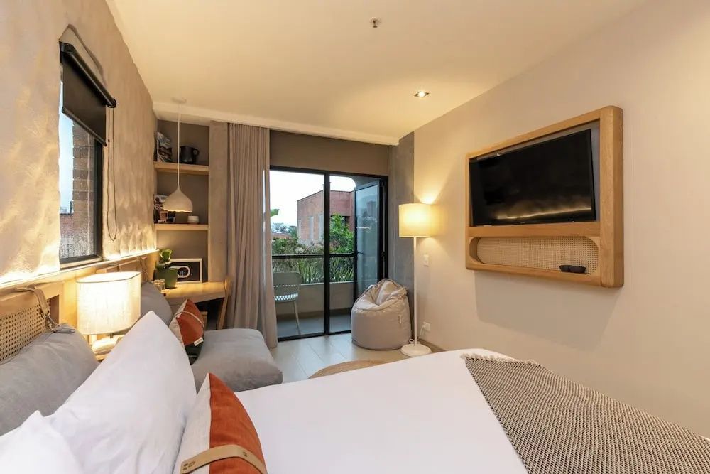 Doppelbett und Flachbildfernseher in einem modern gestalteten Hotelzimmer.