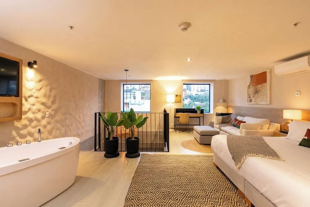 Geräumige Suite mit freistehender Badewanne, Wohnbereich, Schreibtisch und Sitzgelegenheit.