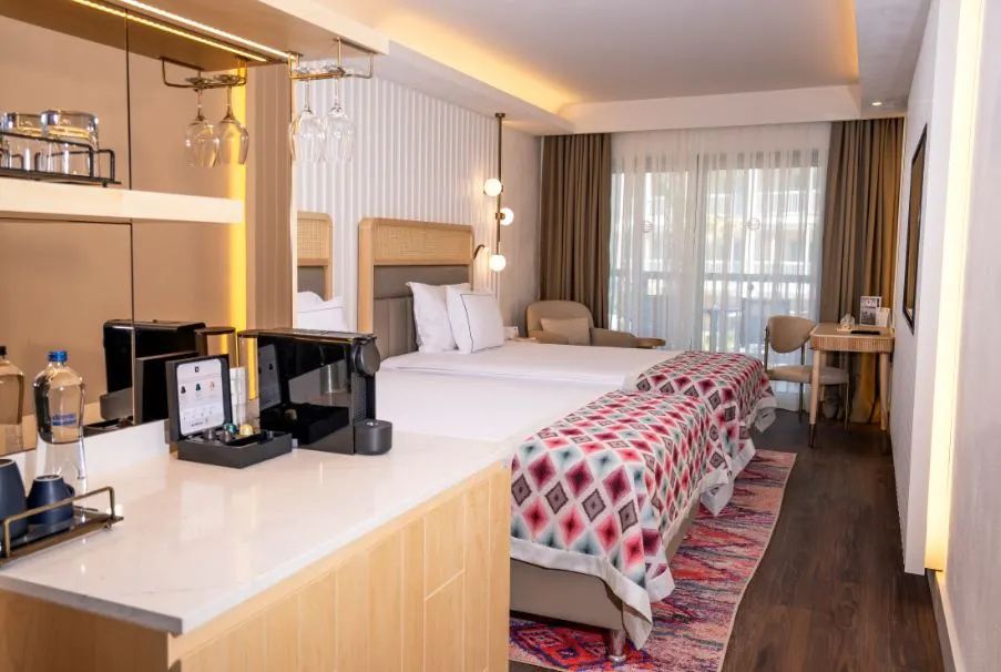 Modernes Hotelzimmer mit zwei Einzelbetten, gemusterten Tagesdecken und Kaffeemaschine.