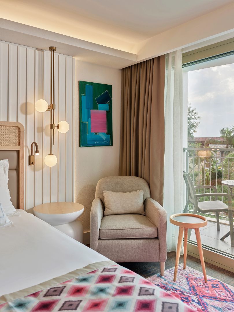 Sitzecke im Hotelzimmer mit Sessel, Beistelltisch und Kunstwerk an der Wand.