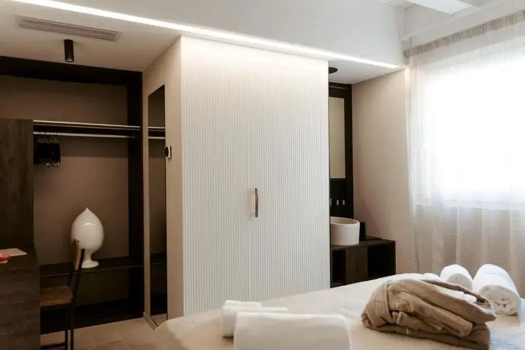 Weißer Lamellenschrank und offene Garderobe mit indirekter LED Beleuchtung im Zimmer.