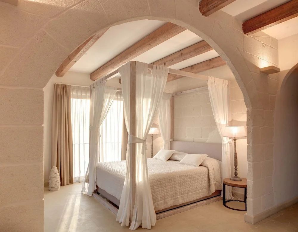 Schlafzimmer mit großem Himmelbett unter einer gewölbten Steinarchitektur und einer Holzbalkendecke.