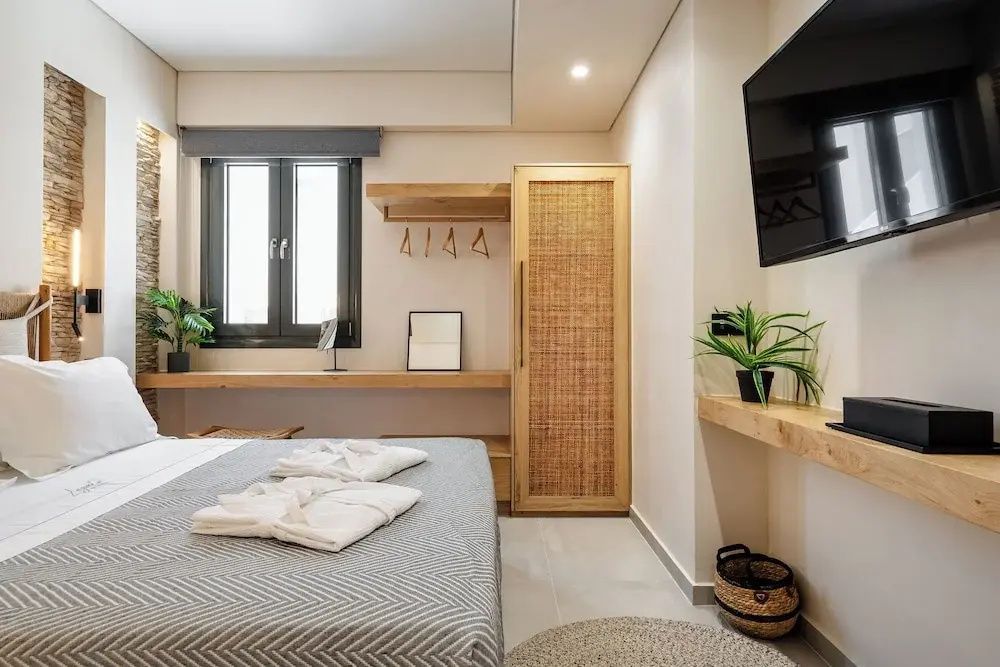 Hell eingerichtetes Schlafzimmer mit Doppelbett, Holzmöbeln und Flachbild-TV