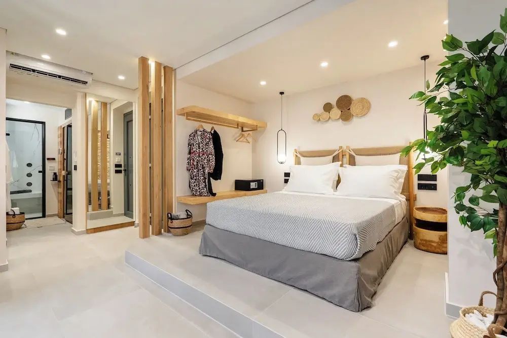 Doppelbett auf einem erhöhten Podest neben einer offenen Garderobe aus Holz mit Kleiderbügeln.
