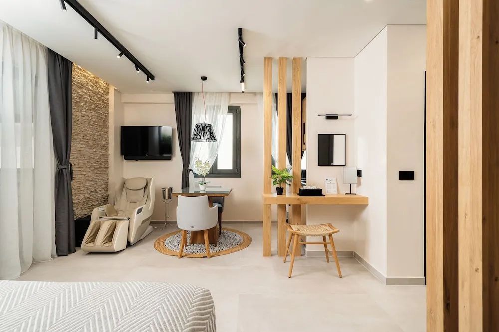 Innenansicht der Suite mit kleinem Esstisch, hellem Massagesessel und offenem Arbeitsbereich.