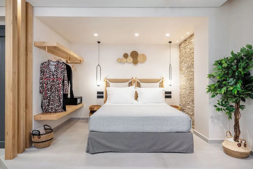Doppelbett mit zwei Kissen und weißer Bettwäsche vor einer Wand mit Holzregal und Wandleuchten.