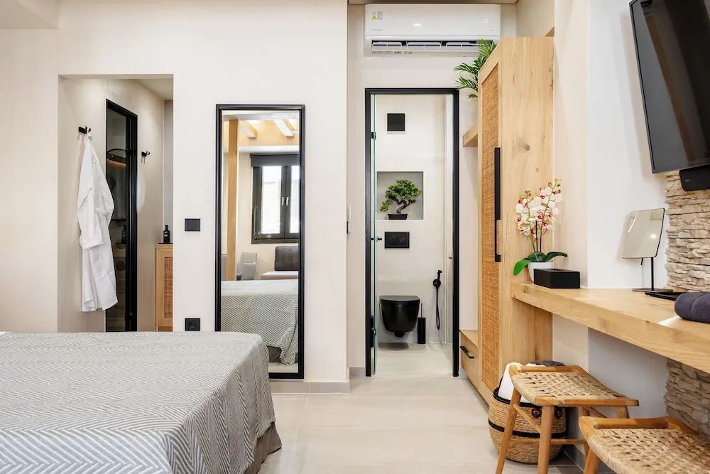 Modernes Zimmer mit Blick auf Kleiderschrank, Ganzkörperspiegel und angrenzendes Bad.