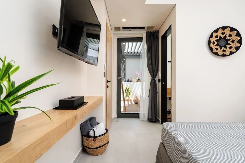Schmaler Eingangsbereich einer modern eingerichteten Suite mit Fernseher und Blick zur Terrasse.