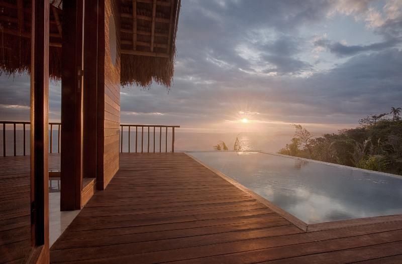 Infinitypool auf einer Holzterrasse mit Blick auf das Meer bei Sonnenuntergang.