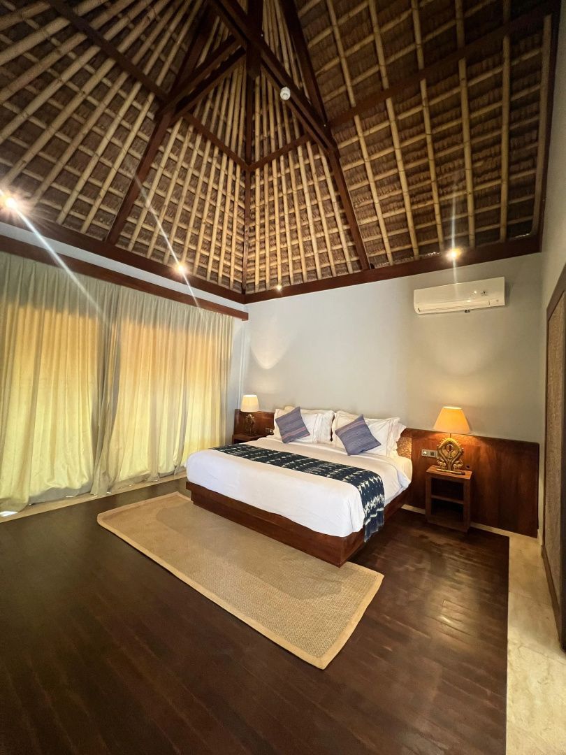 Schlafzimmer mit großem Doppelbett, Holzfußboden und hoher Decke im traditionellen Stil.