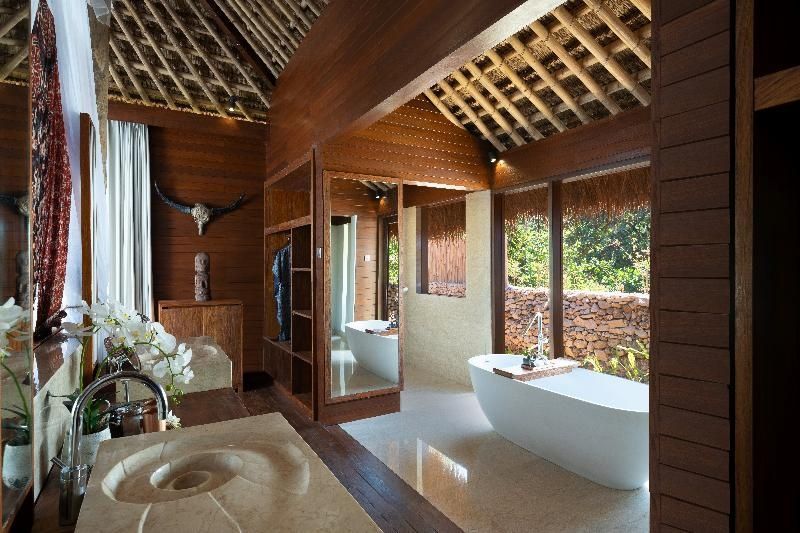 Badezimmer mit frei stehender Badewanne und Waschbecken aus Stein.