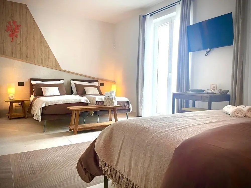 Ein modern gestaltetes Schlafzimmer mit Betten und einem Tisch neben dem Fenster.