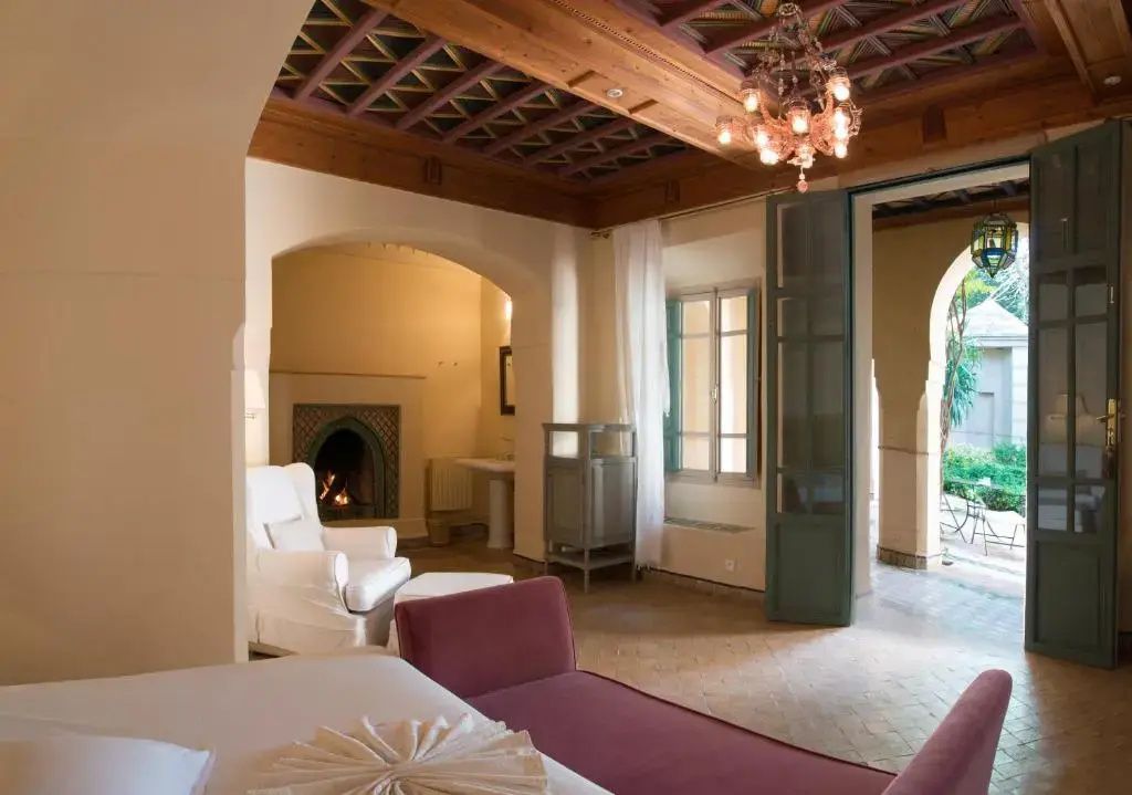Wohnbereich einer Suite mit verzierter Holzdecke, Kamin und Zugang zur Terrasse.