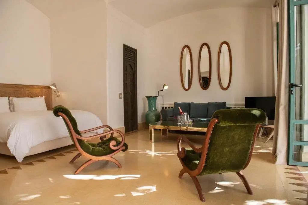 Geräumiger Wohnbereich einer Suite mit grünen Sesseln, Couch, Couchtisch und spiegelnder Deko.