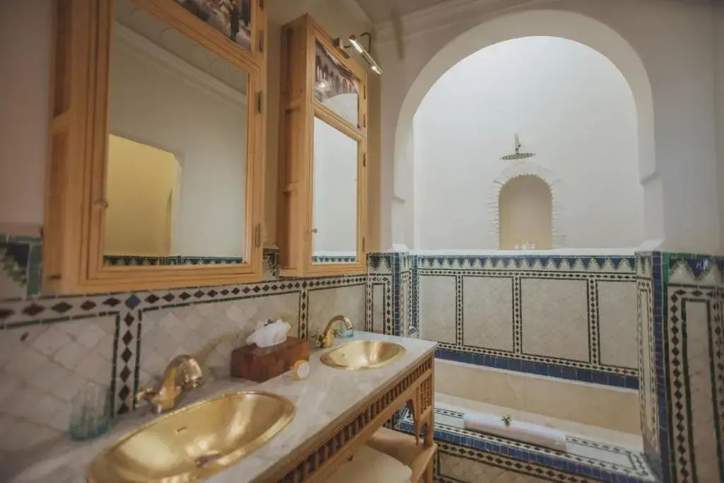 Badezimmer mit zwei goldfarbenen Waschbecken und marokkanischen Fliesen.