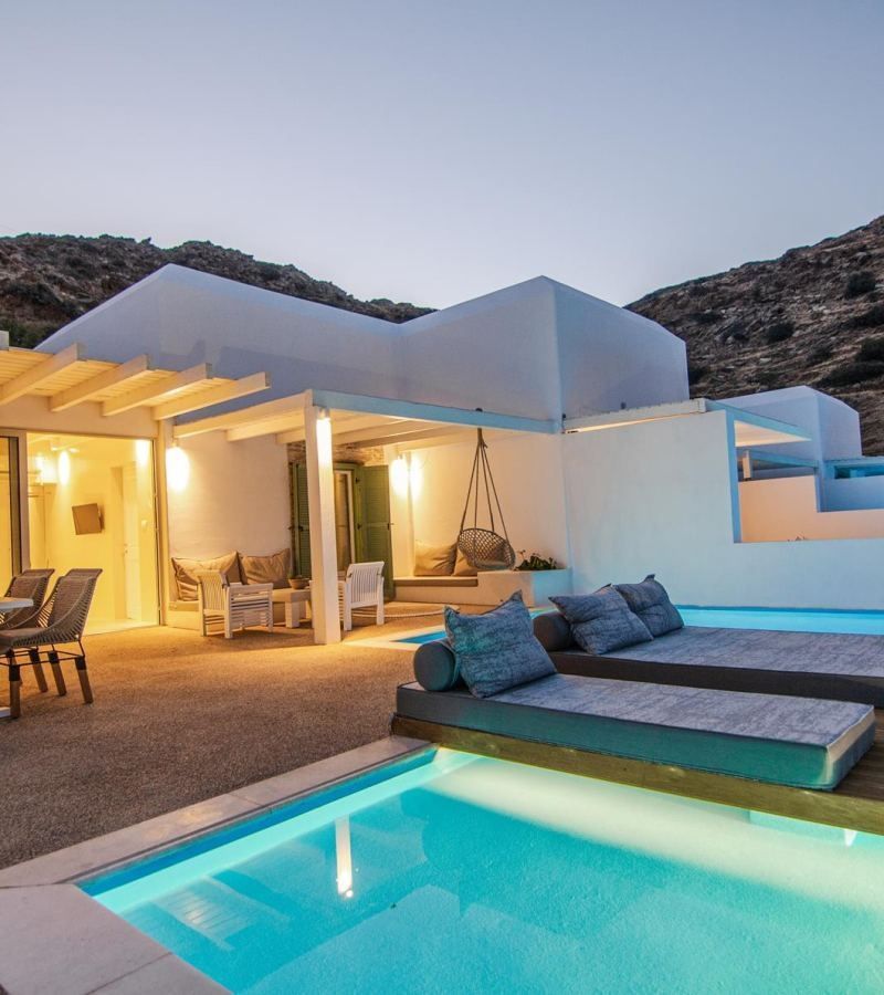 Sonnenterrasse mit privaten Pools, Liegekissen und Blick auf ein weißes Gebäude.