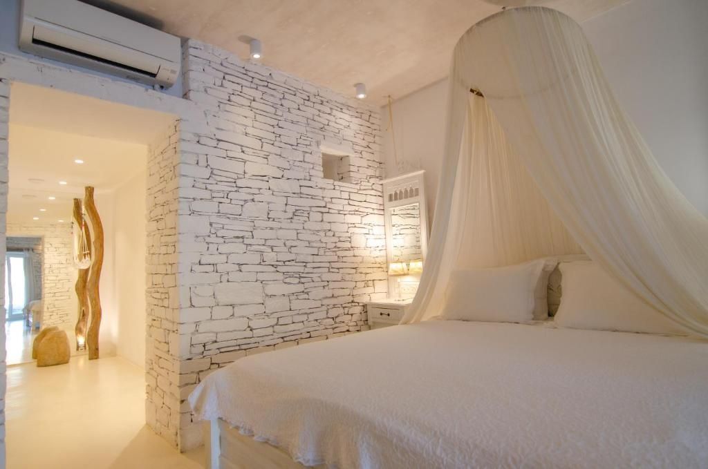 Helles Hotelzimmer mit einer charakteristischen Natursteinwand und einem Bett mit Baldachin.