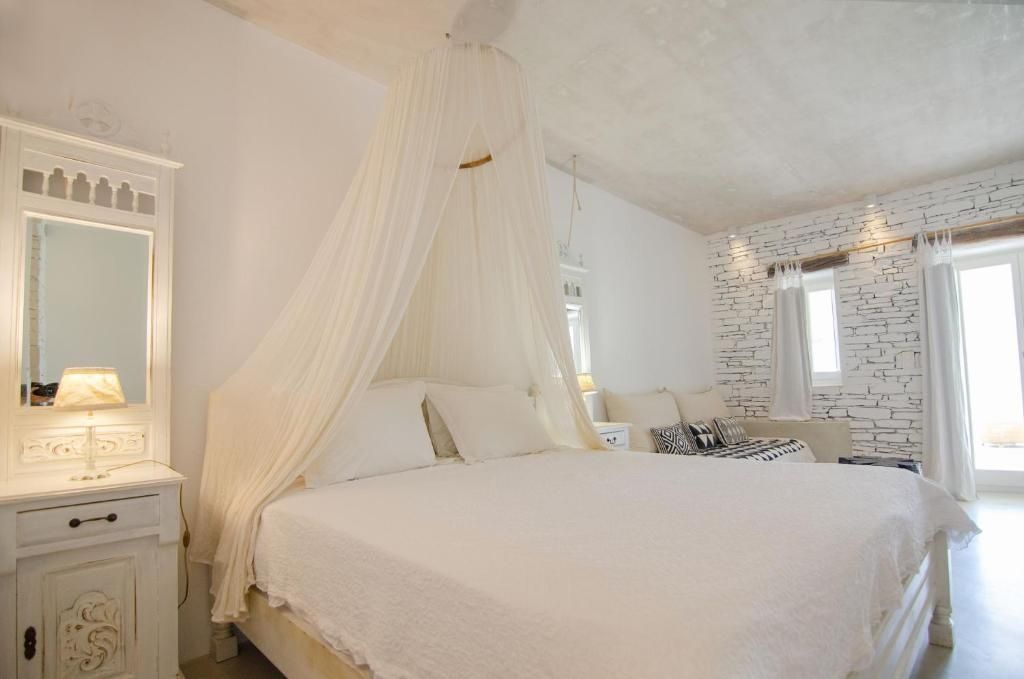Weiß gestaltetes Schlafzimmer mit einem Baldachinbett und Blick auf eine Steinecke.