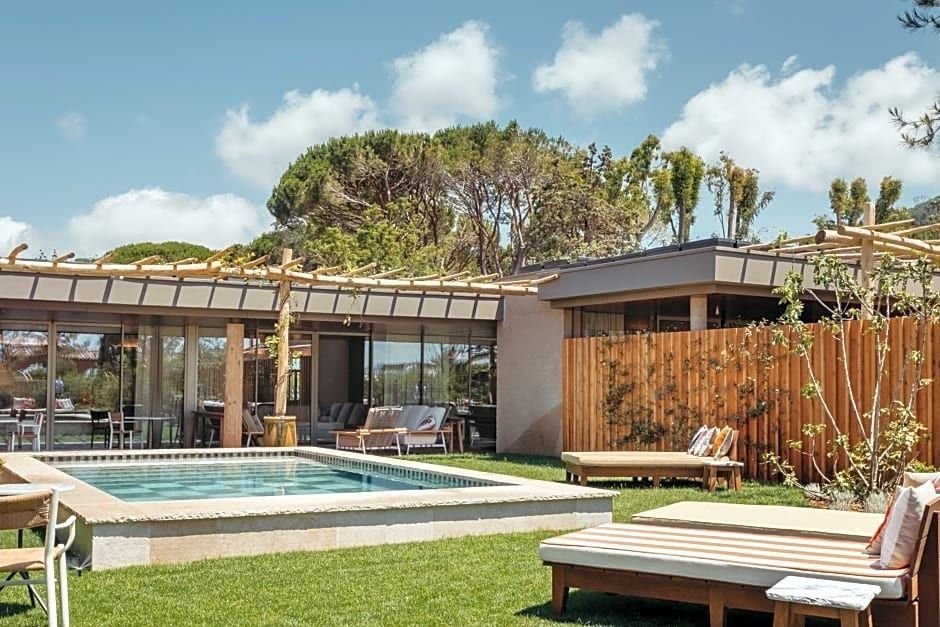 Außenbereich einer Villa mit Swimmingpool, Sonnenliegen auf dem Rasen und Holzüberdachung.