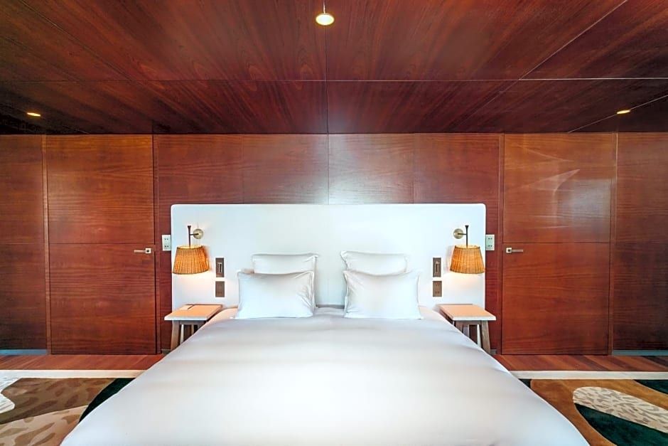 Doppelbett mit weißer Bettwäsche, Holzverkleidung an Wänden und Decke sowie Nachttischlampen.