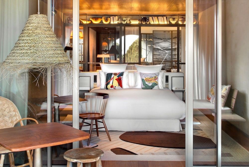 Modernes Hotelzimmer mit Doppelbett, bunten Kissen und transparenten Schiebetüren.
