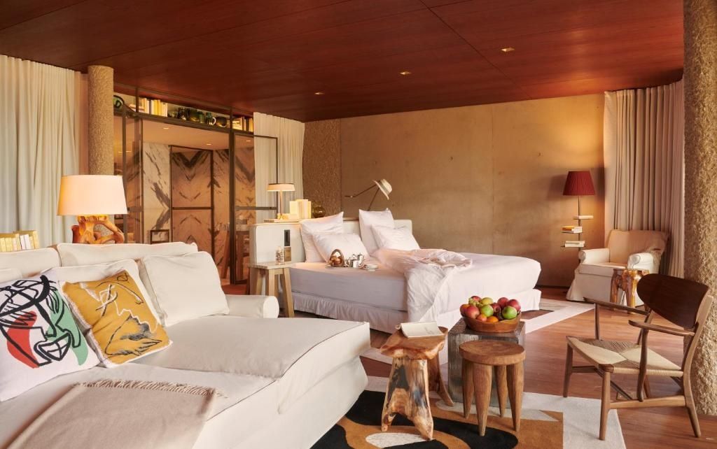 Geräumiges Hotelzimmer mit großem Doppelbett, weichem Sofa und Holzdecke.